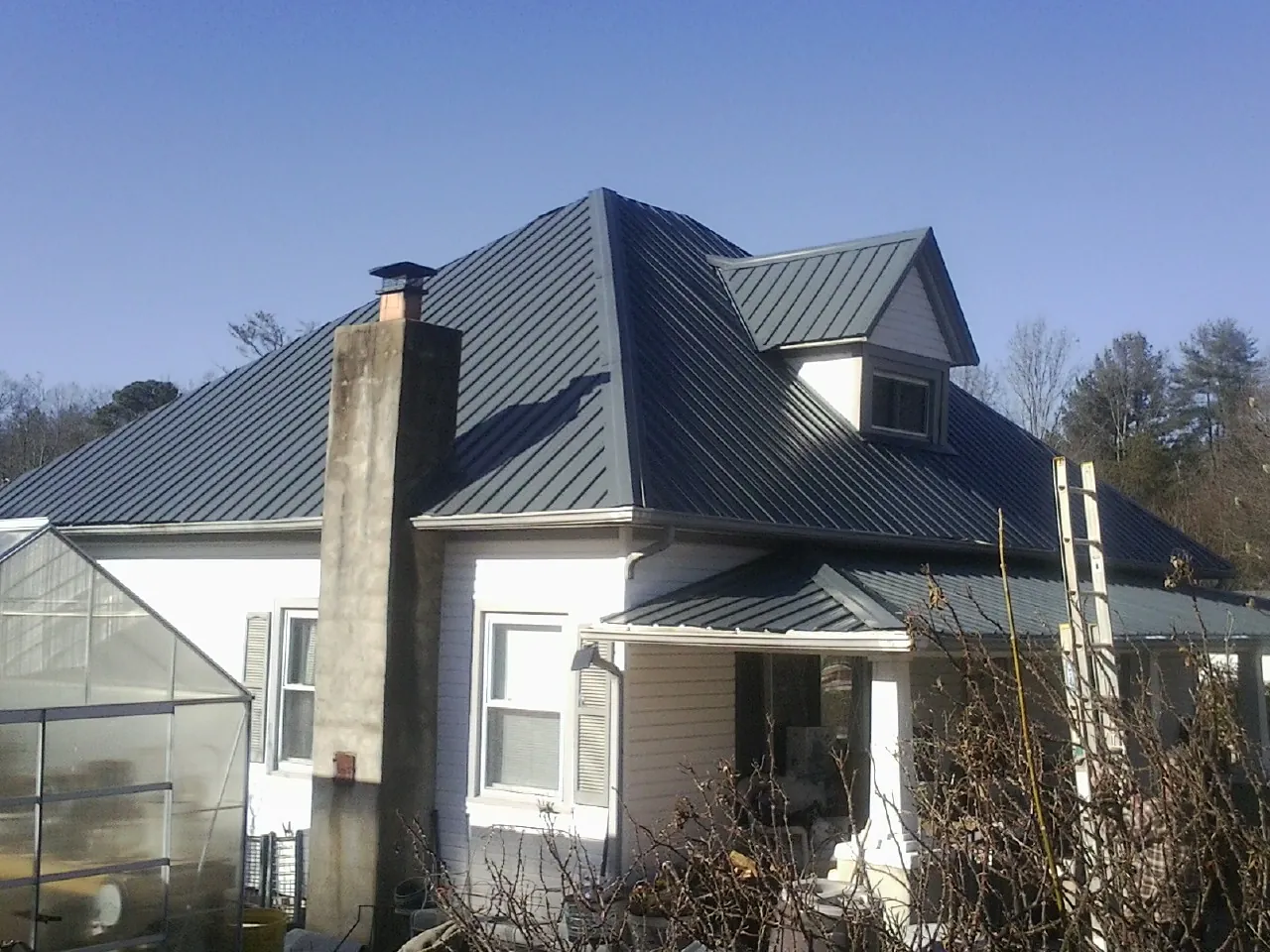 Dark blue standing seam metal roof on a white farmhouse with dormer — Slate & Tile Roof Repair by Roofing Brothers in Waterville Valley