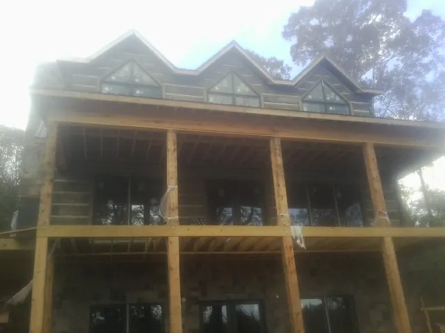 Dormers and porch framing on a large log home under construction — Roof Coating work by our crew in Waterville Valley
