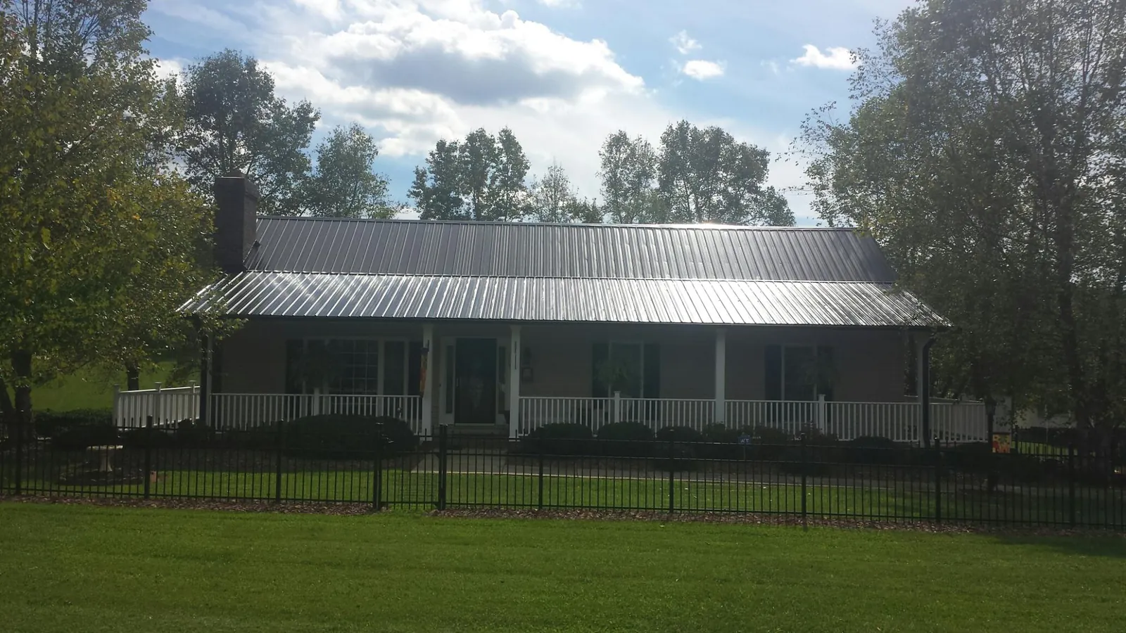Gray metal roof on a brick ranch with a full width front porch — Gutter Guard Installation work by our crew in Waterville Valley