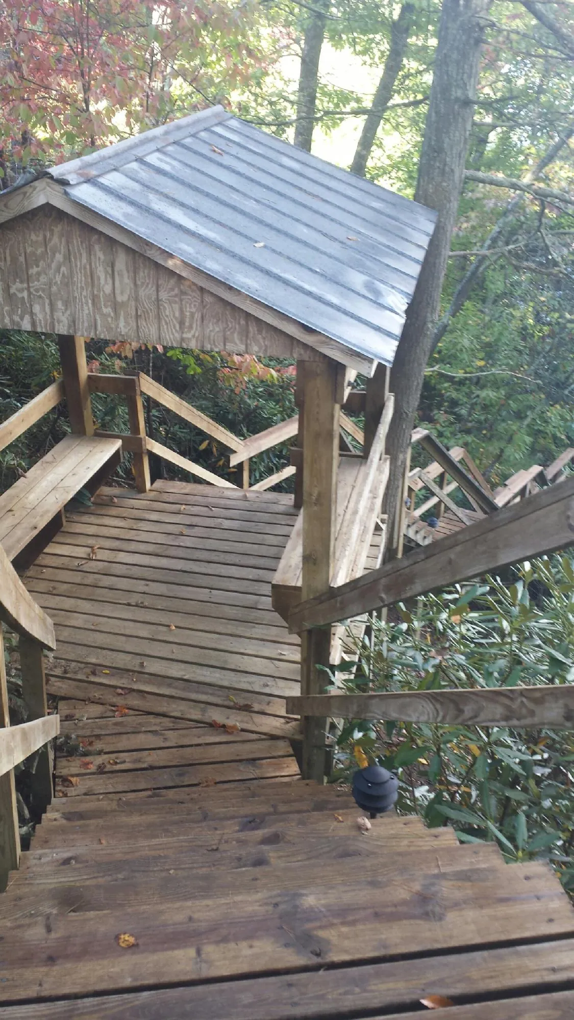 Metal roofed shelter over wooden steps on a wooded walkway — Skylight Repair & Installation work by our crew in Waterville Valley
