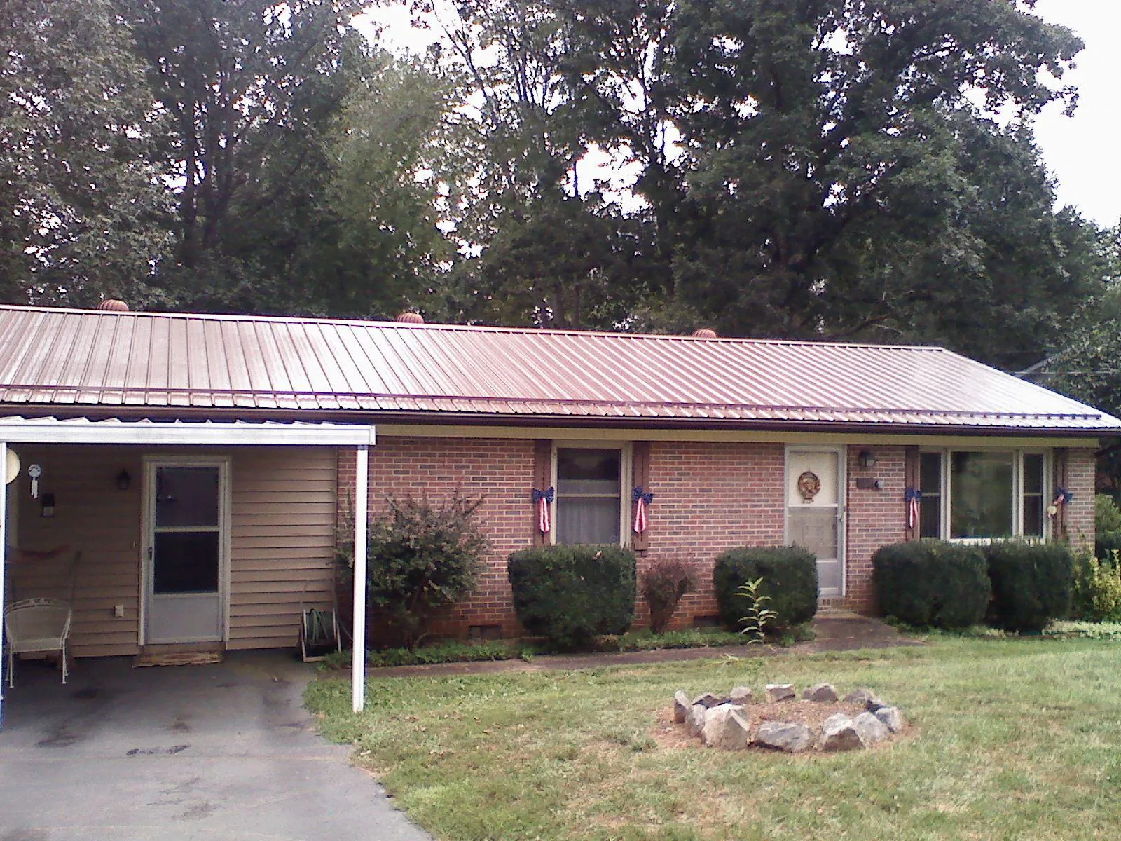 Bronze metal roof and carport on a brick ranch home — Roof Repair work by our crew in Waterville Valley