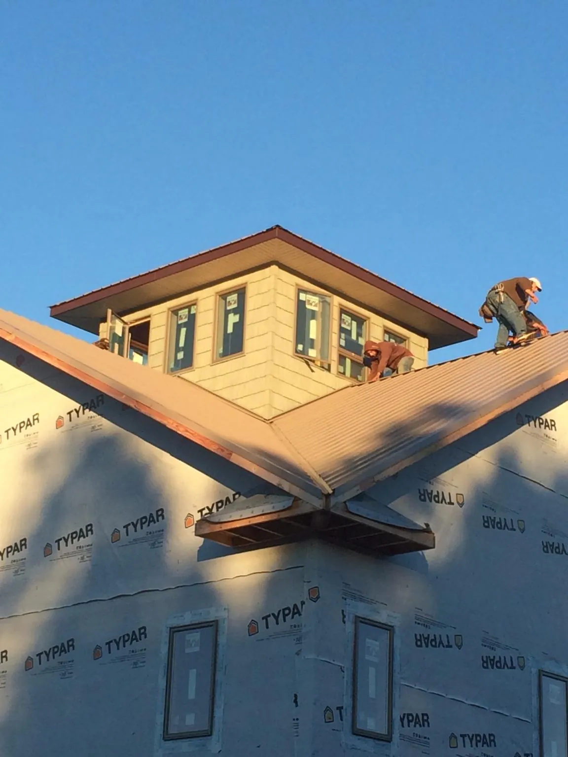 Roofers working around a rooftop cupola on a new metal roof at sunset — Roof Waterproofing in Waterville Valley by Roofing Brothers